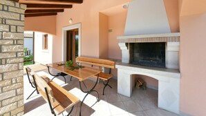 A patio with a stone wall, a wooden table, benches, and a stone fireplace. - House 377/857 (Istria - Sveti Lovreč), 18000m from the beach (Sveti Lovreč)