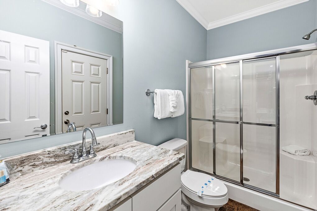 A bathroom with a marble sink, a toilet, and a glass-enclosed shower.