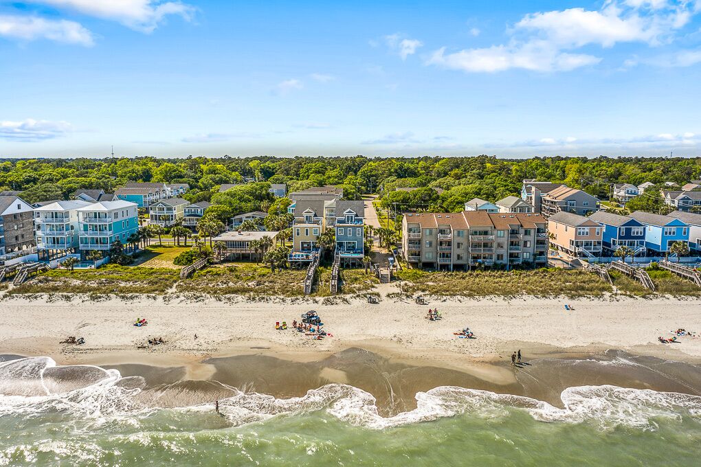 A coastal residential area with beachfront properties, including houses and a beach with people and beachgoers.