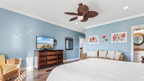 A bedroom with a large bed, wooden dresser, wicker chair, and a ceiling fan. - 6BR Home w/ Private Pool & Ocean Views (Garden City Beach)