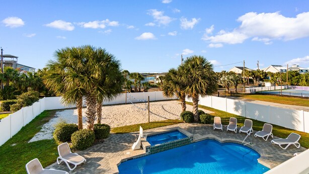 A swimming pool with lounge chairs, palm trees, and a white fence. - 6BR Home w/ Private Pool & Ocean Views (Garden City Beach)