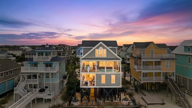 A multi-story beachfront house with balconies, a pool, and a dock.