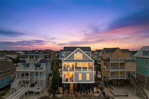 Une maison à plusieurs étages située en bord de mer, dotée de balcons, d’une piscine et d’un quai.