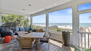 A covered outdoor seating area with a wooden table and chairs, a cushioned sofa, and a large planter. - 7BR Home Near Surfside Pier w/ Private Pool & Wi-Fi (Surfside Beach)