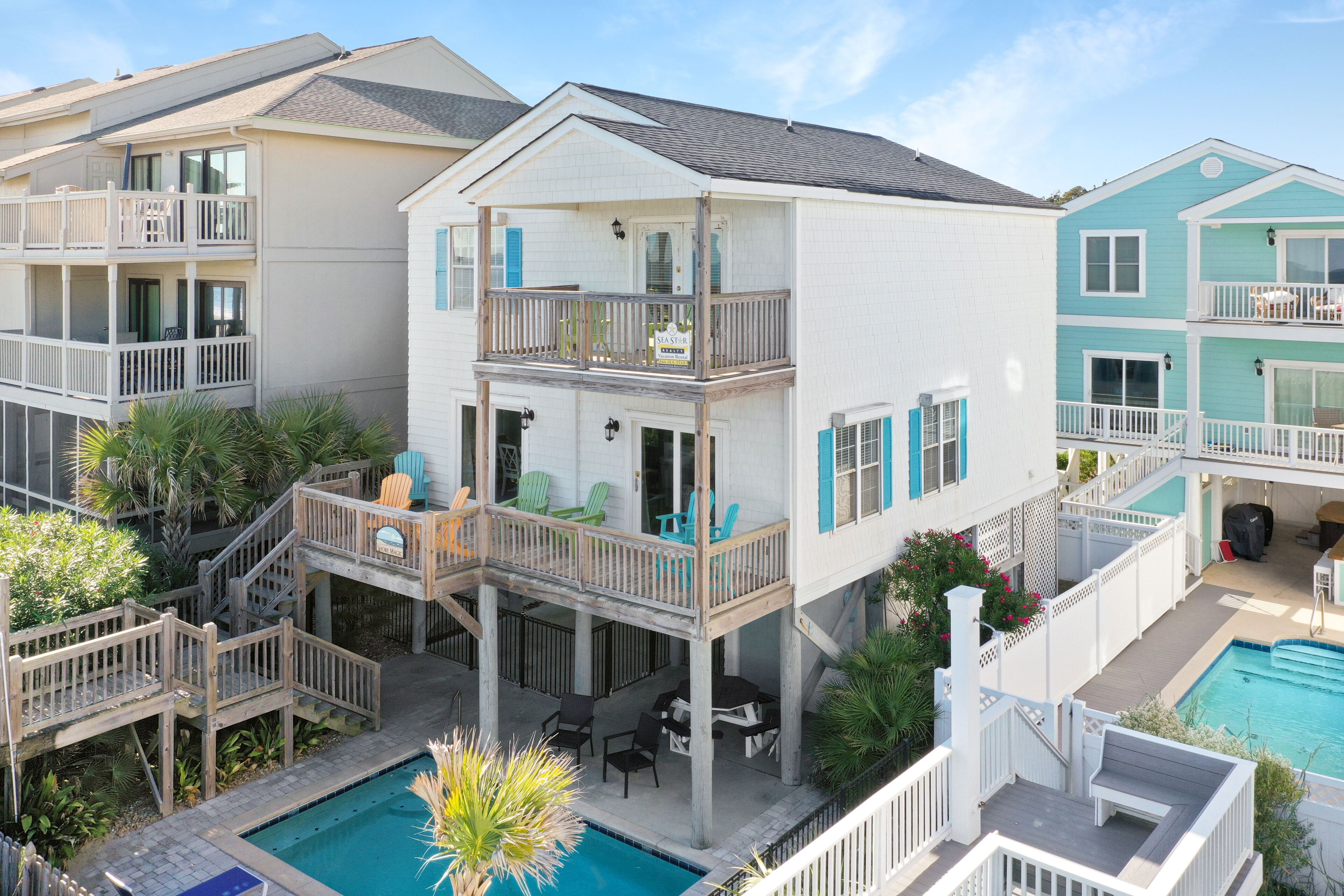 A multi-story residential building with a balcony, a pool, and outdoor seating.
