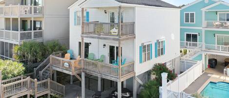 A multi-story residential building with a balcony, a pool, and outdoor seating.