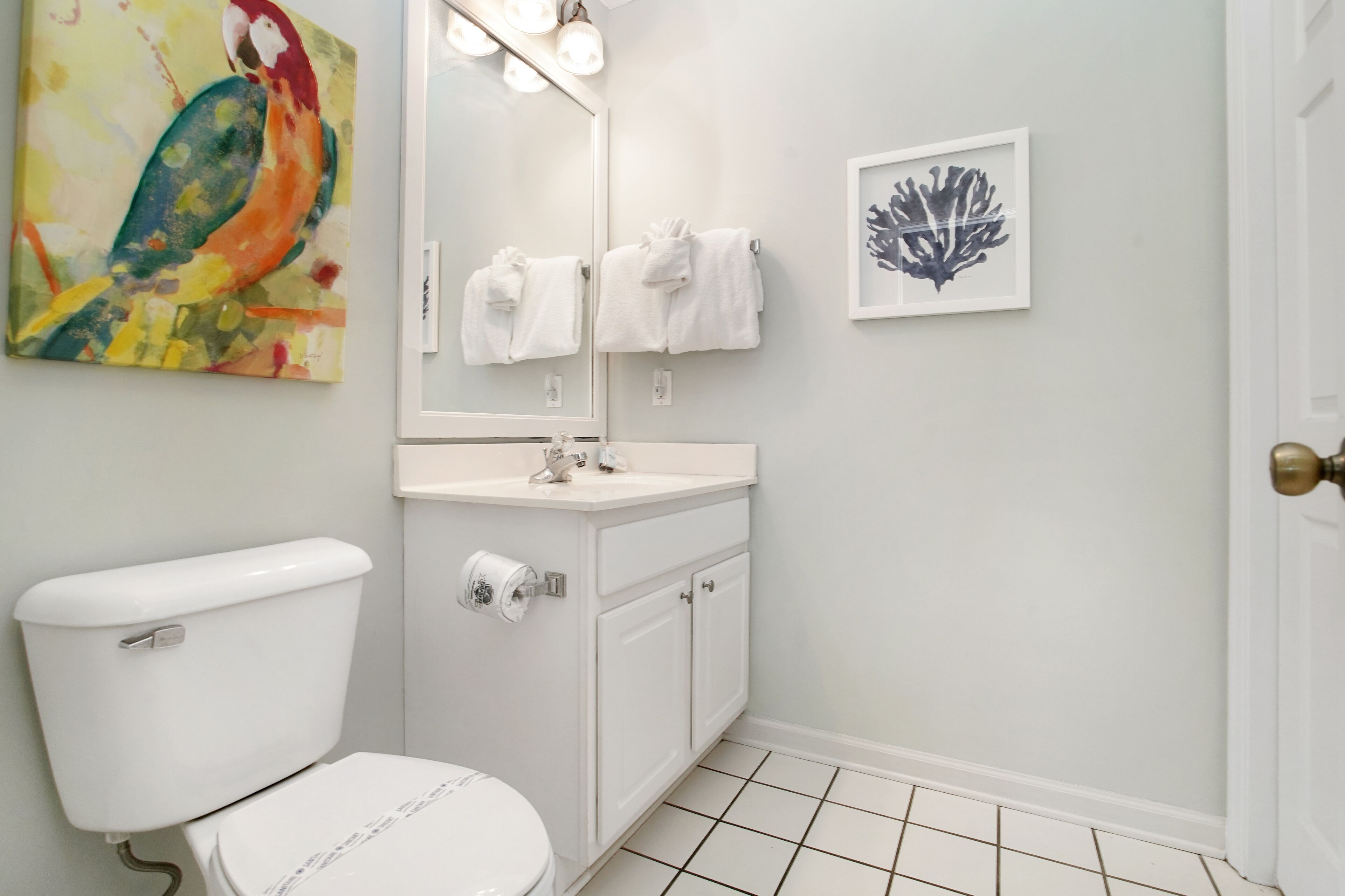 Een badkamer met toilet, wastafel, spiegel en handdoeken.