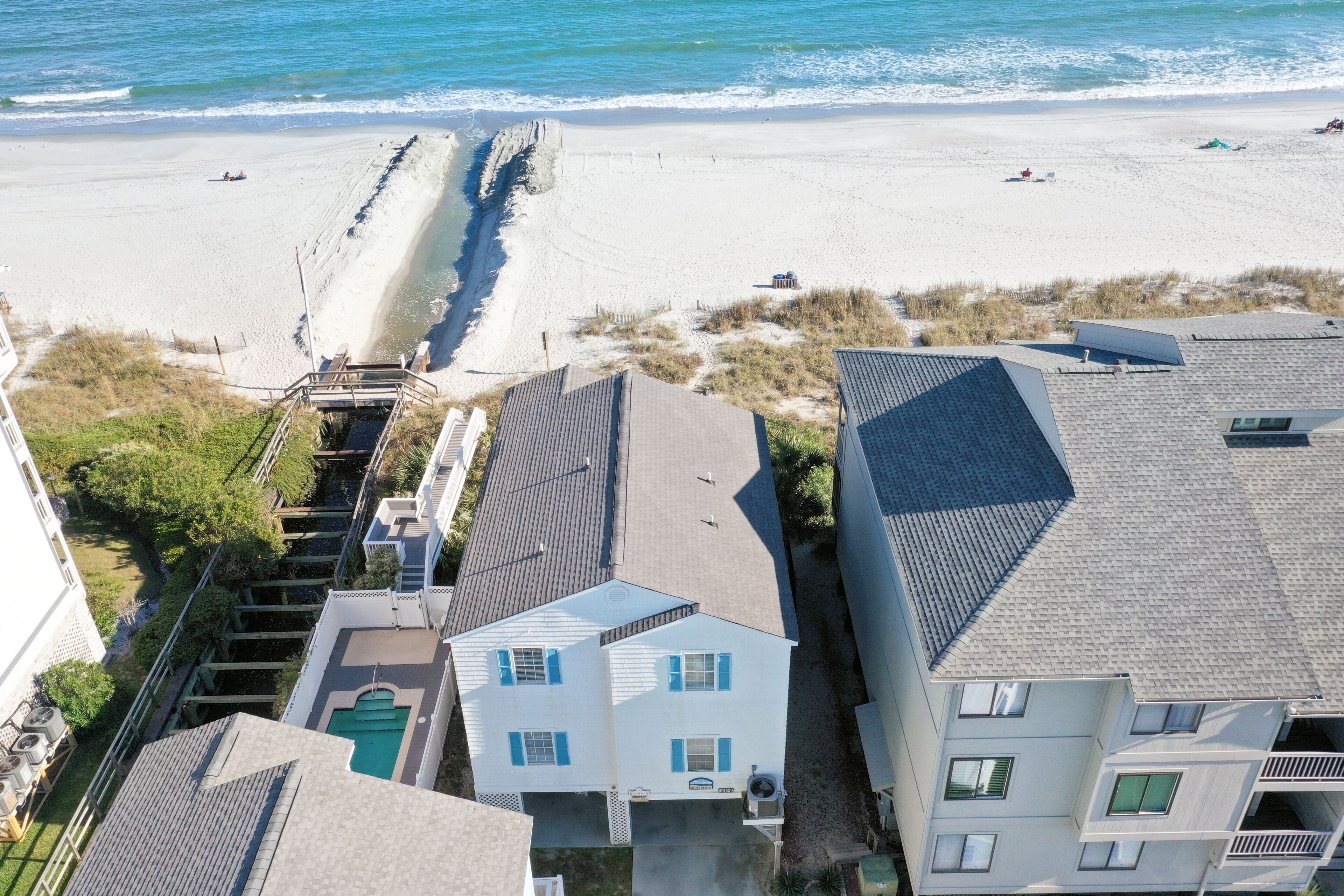 A coastal residential area with houses, a beach, and a pier.