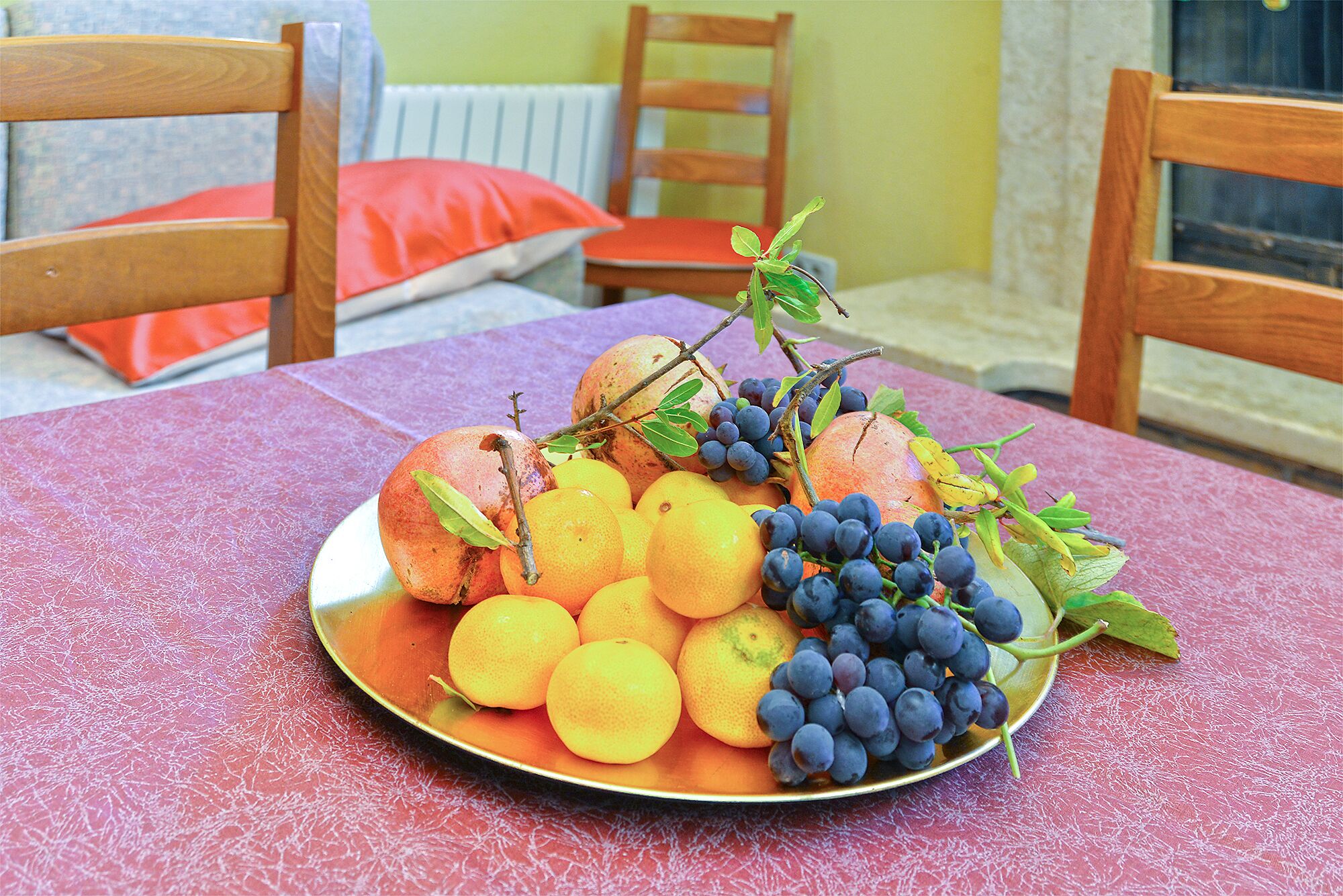 A table with a fruit platter containing peaches, oranges, and grapes.