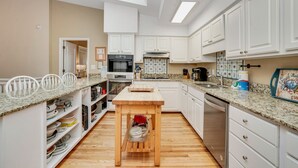 Uma cozinha moderna com armários brancos, uma mesa de madeira e diversos eletrodomésticos.