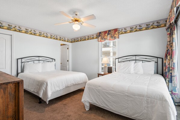A bedroom with two beds, a ceiling fan, a window with blinds, and a door. - Beach House with Private Beach Access & Balcony (Surfside Beach)