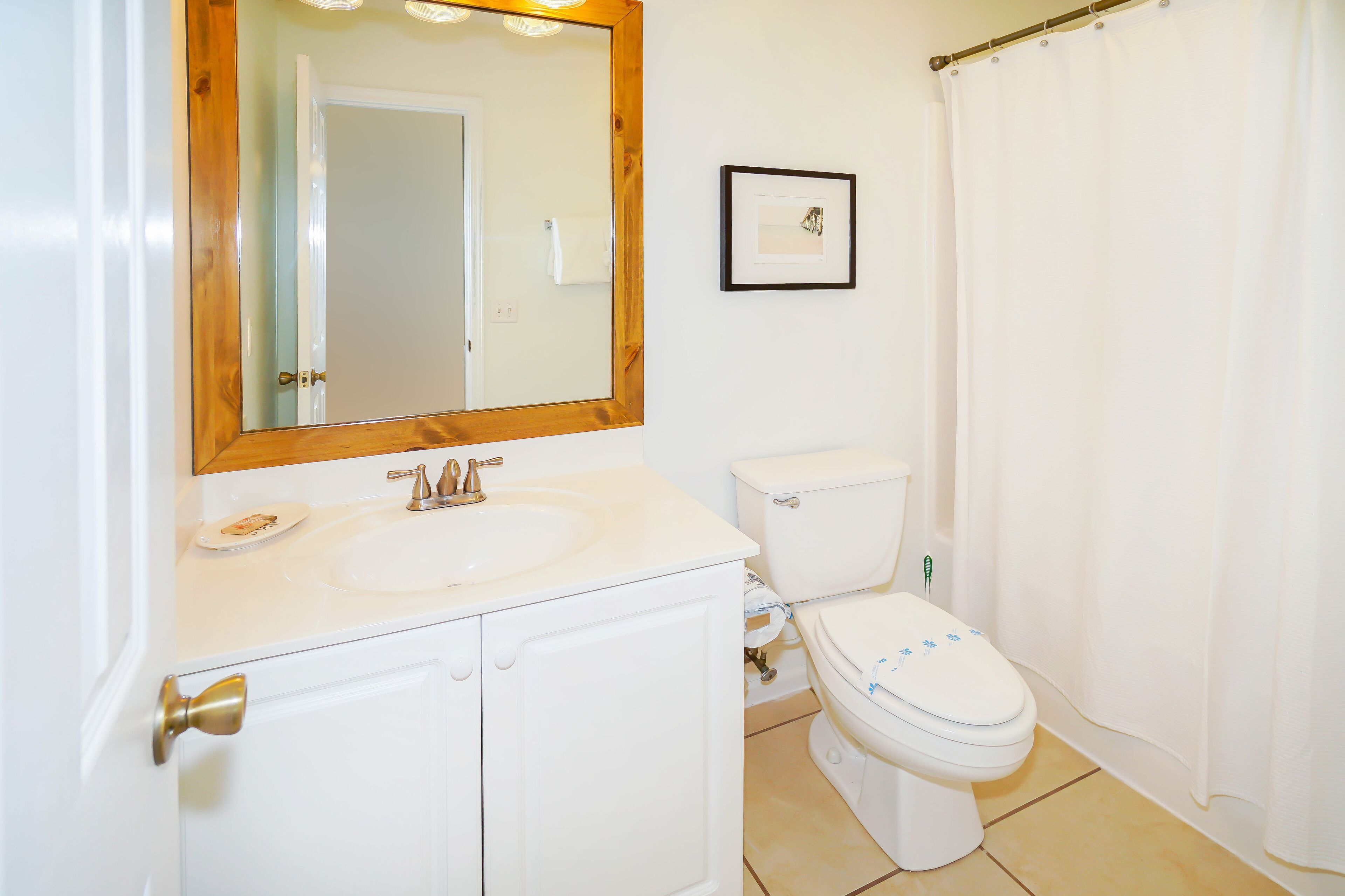 A bathroom with a white sink, a toilet, and a shower curtain.
