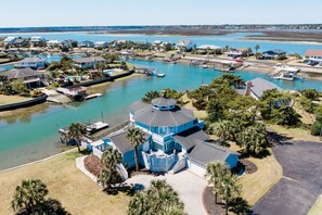 A coastal residential area with a prominent blue house featuring a circular tower, surrounded by water and other houses. - Inlet Front 5BR Home w/ Private Dock & Walk to Beach (Garden City Beach)