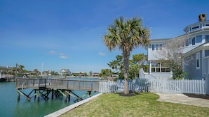 A waterfront property with a wooden dock, a white picket fence, and a palm tree. - Inlet Front 5BR Home w/ Private Dock & Walk to Beach (Garden City Beach)