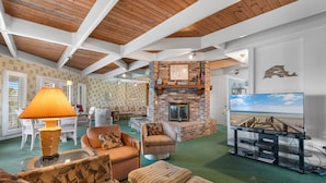 A spacious living room with a fireplace, comfortable seating, a television, and a view of the outdoors. - Inlet Front 5BR Home w/ Private Dock & Walk to Beach (Garden City Beach)