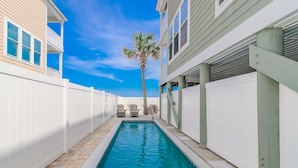A swimming pool with a white fence, a palm tree, and two chairs. - 7BR Beach House with Private Pool and Beach Access (Garden City Beach)
