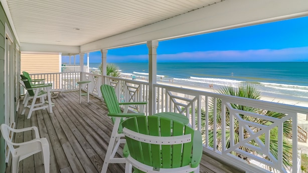 A wooden deck with green chairs and a white railing overlooking a beach. - 7BR Beach House with Private Pool and Beach Access (Garden City Beach)