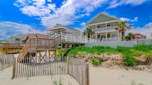 A beachfront property with a wooden deck, a white fence, and a sandy beach. - 7BR Beach House with Private Pool and Beach Access (Garden City Beach)