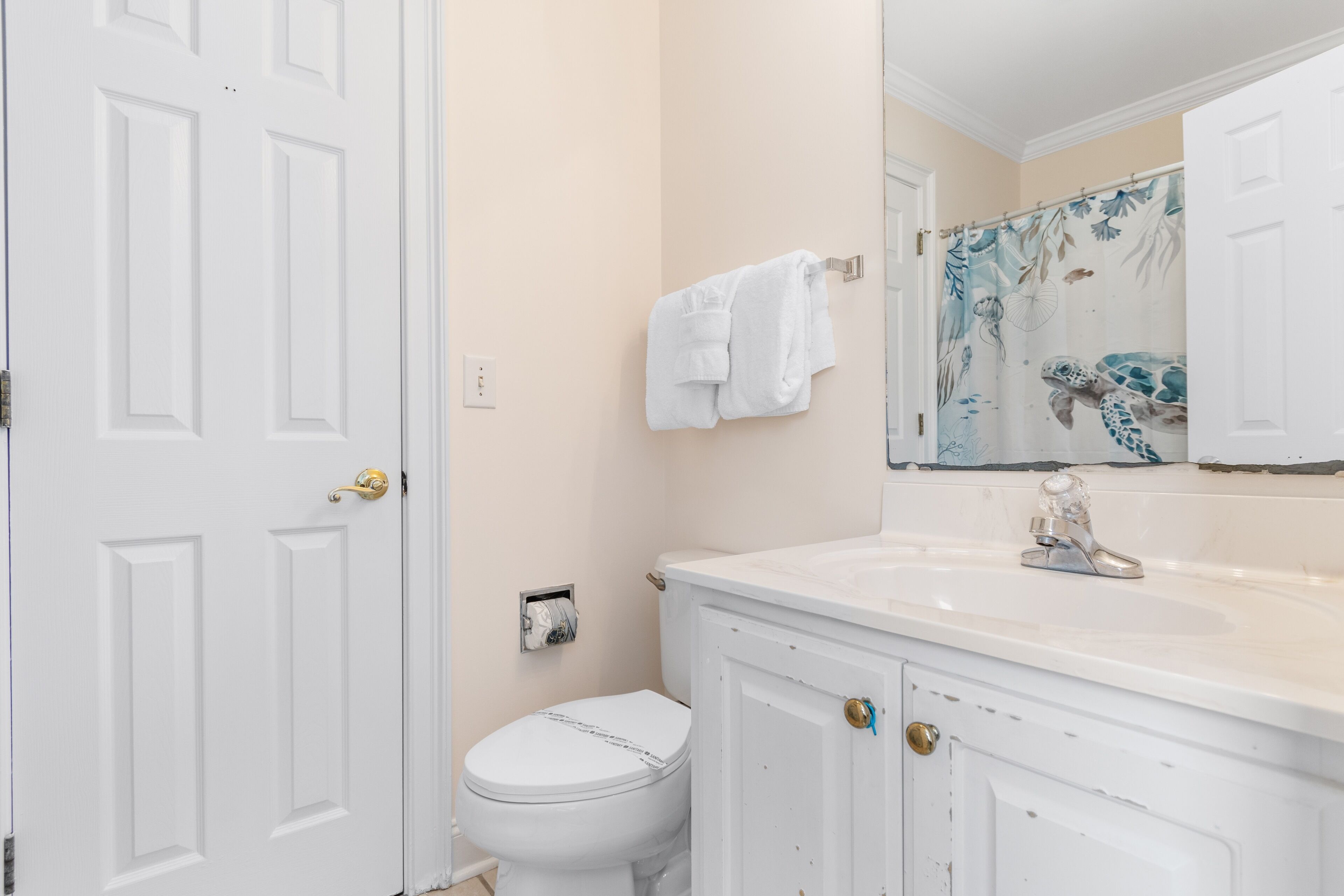 A bathroom with a white toilet, a sink with a mirror above it, and a towel hanging on a rack.