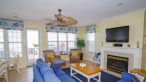A living room with a blue sofa, a wooden coffee table, and a fireplace. - 5BR House with Private Pool Near Surfside Pier (Surfside Beach)