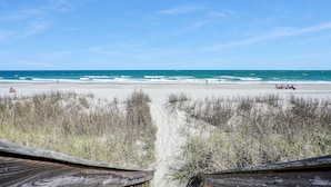 A beach with a wooden boardwalk leading to the shore, clear skies, and the ocean. - Condo w/ Beach Walkover & Resort Pool Access (Surfside Beach)