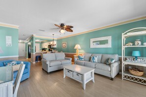 A living room with two sofas, a coffee table, and a ceiling fan.