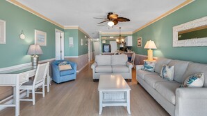 A living room with a ceiling fan, a dining table with chairs, a sofa, and a coffee table. - Condo w/ Beach Walkover & Resort Pool Access (Surfside Beach)