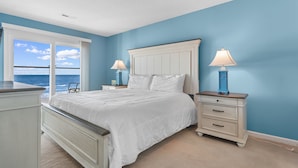 A bedroom with a large bed, two bedside tables with lamps, a dresser, and a view of the ocean. - Condo w/ Beach Walkover & Resort Pool Access (Surfside Beach)