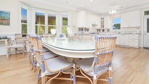 A spacious kitchen with white cabinets, a round glass table, and wicker chairs. - Ocean View 6-Bedroom Beach Haven Sleeps 17 Near North Litchfield (North Litchfield)
