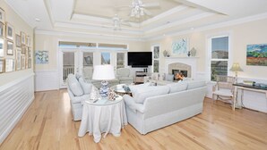 A spacious living room with a large sofa, a coffee table, and a fireplace. There are ceiling fans, a television, and a dining table with chairs. - Ocean View 6-Bedroom Beach Haven Sleeps 17 Near North Litchfield (North Litchfield)