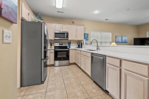 Fully equipped kitchen with stainless steel appliances, large island, and ample countertop space.