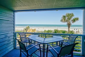 A balcony with a glass table and chairs overlooking a beach. - Condo in Surfside Beach w/ Pool & Beach Access (Surfside Beach)