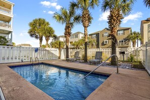 A swimming pool with a white fence, palm trees, and lounge chairs. - Ocean View Duplex Near Surfside Pier - 5 Bedrooms, Sleeps 14 (Surfside Beach)