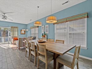 A dining area with a wooden table and chairs, a ceiling fan, and a view of the outdoors. - Ocean View Duplex Near Surfside Pier - 5 Bedrooms, Sleeps 14 (Surfside Beach)