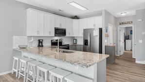 A modern kitchen with white cabinets, granite countertops, and stainless steel appliances. - 5BR Ocean-Side Home w/ Private Pool & Ocean Views Near Surfside Pier (Surfside Beach)