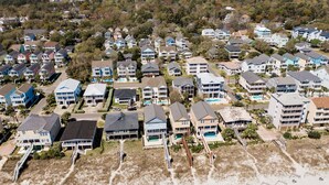 An aerial view of a coastal residential area with multiple two-story houses, some with balconies, and a beach in the foreground. - 5BR Ocean-Side Home w/ Private Pool & Ocean Views Near Surfside Pier (Surfside Beach)