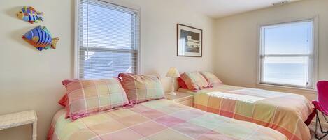 A bedroom with two beds, a ceiling fan, and a window with blinds.