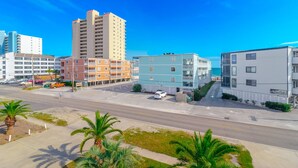 A coastal urban area with multi-story buildings, a parking lot, and palm trees. - Walk to Beach 6BR Home w/ Private Pool & Ocean Views (Garden City Beach)