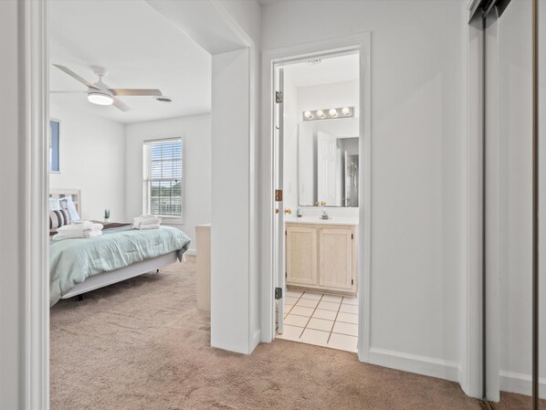 Een slaapkamer met een bed, een plafondventilator en een raam met jaloezieën.