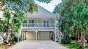 A two-story house with a covered garage, a balcony, and a well-maintained lawn.