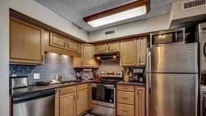 A compact kitchen with wooden cabinets, stainless steel appliances, and a built-in microwave. - Condo in Garden City Beach with Stunning Views & Beach Access (Garden City Beach)