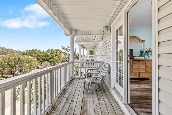 A wooden porch with a railing, a view of the surrounding area, and a glimpse of the interior with a dresser and mirror. - Walk to Beach: 5BR Surfside Beach Home w/ Private Pool (Surfside Beach)