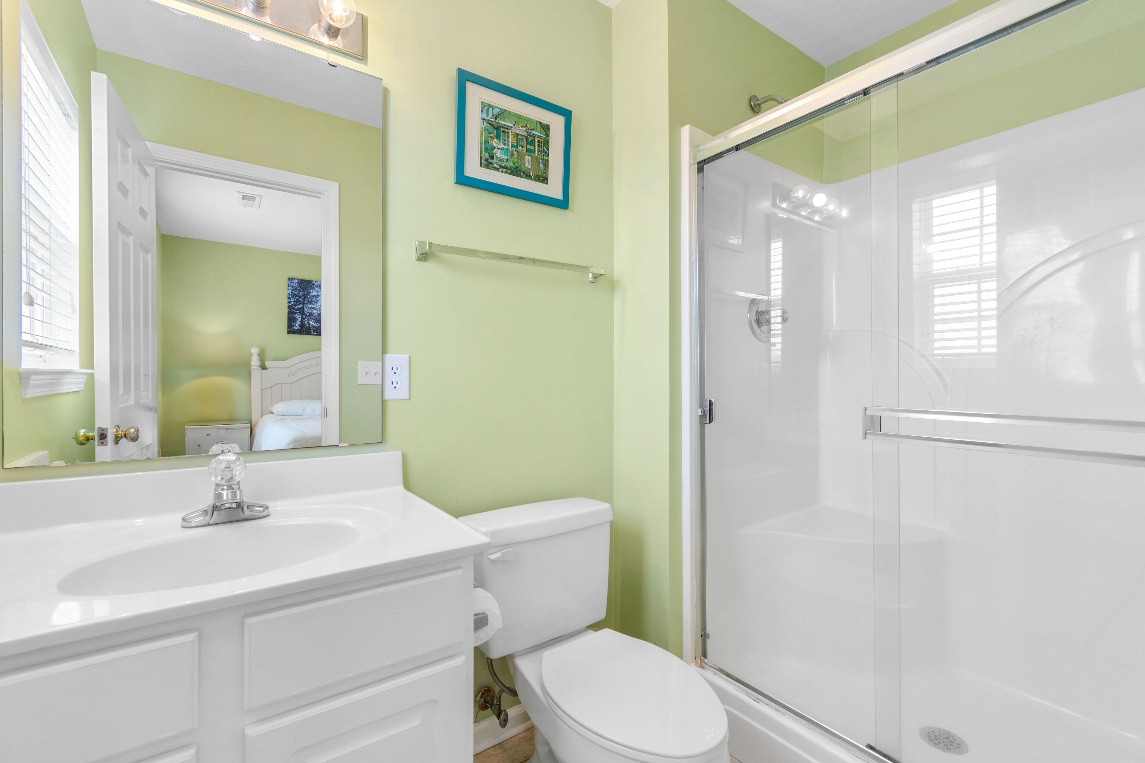 A bathroom with a white sink, toilet, and glass shower enclosure.