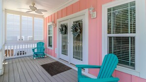 Un portico coperto con sedie color acquamarina, una ventola a soffitto e una ringhiera bianca.