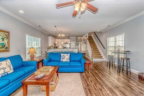 Relax in this stylish living area with a sofa, coffee table, and staircase leading to an upper level.