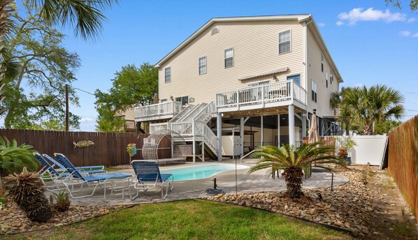 A two-story house with a pool, outdoor seating, and a fenced backyard.
