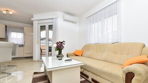 A modern living room with a beige sofa, a glass coffee table, and a dining area with a white table and chairs. - Apartment 396/902 (Istria - Medulin), 300m from the beach (Medulin)