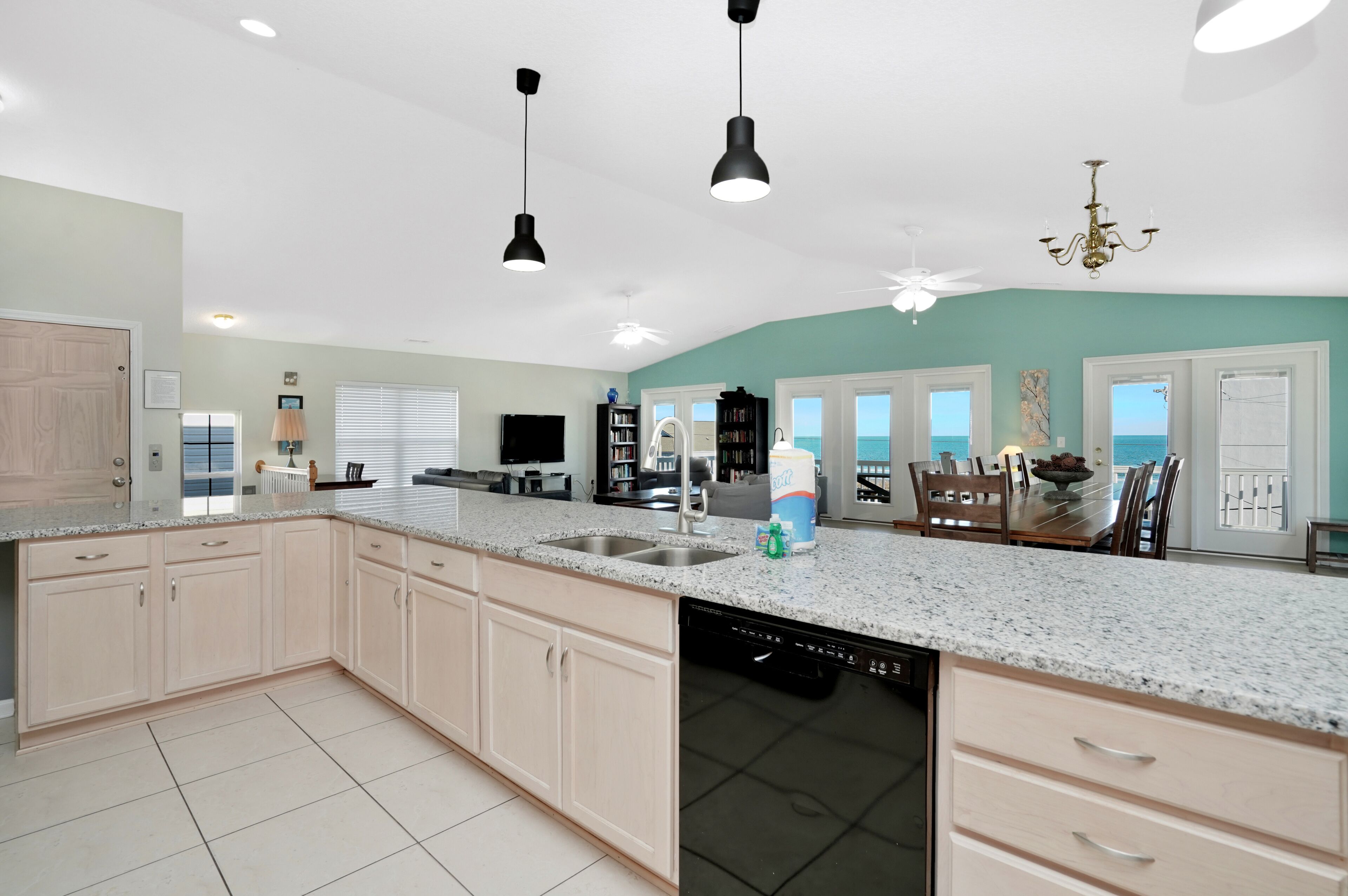 A spacious kitchen with granite countertops, a dishwasher, and a dining area with a view of the ocean.
