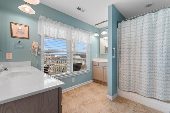 A bathroom with a large sink, vanity, and a shower with a patterned curtain. - 5-Bedroom Home Near Surfside Pier w/ Private Pool & Ocean Views (Surfside Beach)