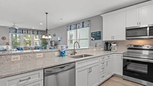 A modern kitchen with white cabinets, a stainless steel dishwasher, a built-in oven, and a microwave. - Walk to Beach Surfside House w/ Pool & 4 Bedrooms (Surfside Beach)